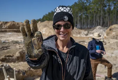 Teacher holding a fossil tooth found during the Montbrook dig